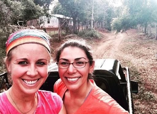 barefoot drifter mom and her friend riding on the back of an open bed truck on a dirt road