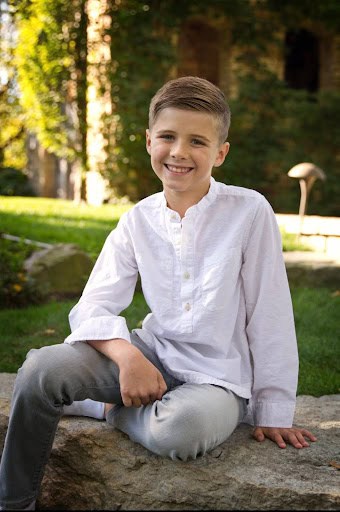 barefoot drifter the boy sitting on rock in white shirt and grey pants, with hand resting on leg