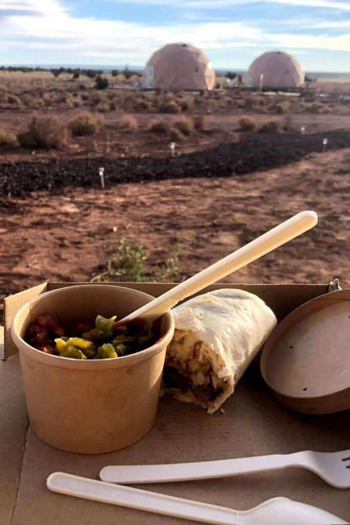 breakfast burrito with a cup of fruit with the desert landscape in the background at Clear Sky Resorts by the Grand Canyon