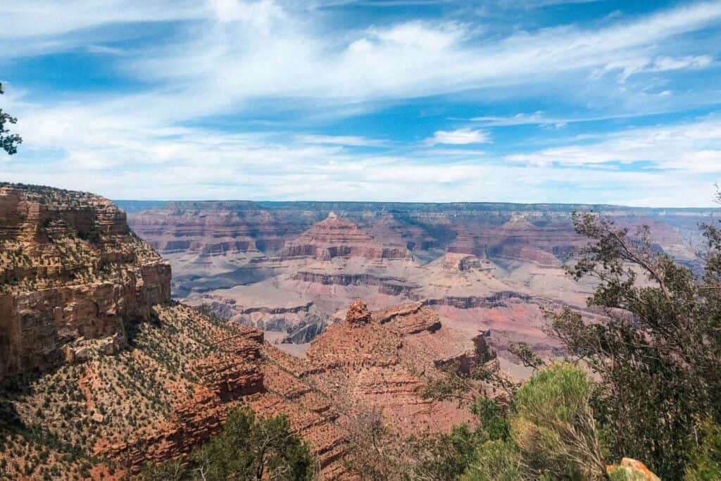 view of the grand canyon valley with a blue sky and white fluffy clouds