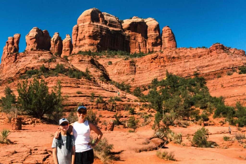 Mother in son wearing hats standing in front of a red rock formation with a blue sky