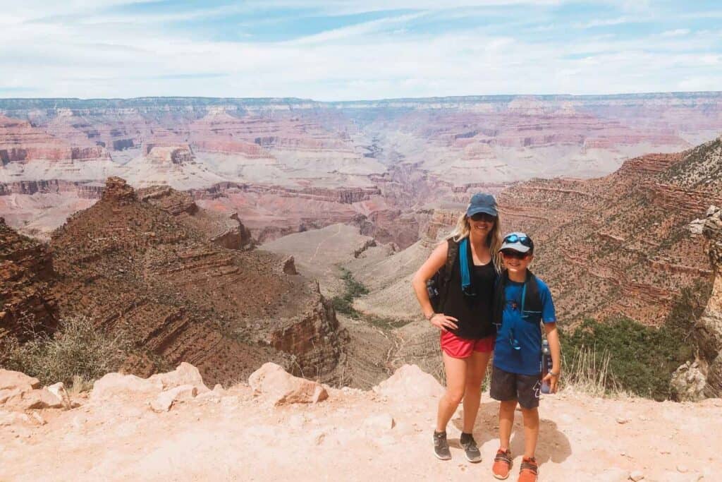 mom and son standing smiling with a red rocky valley and hills behind them 
