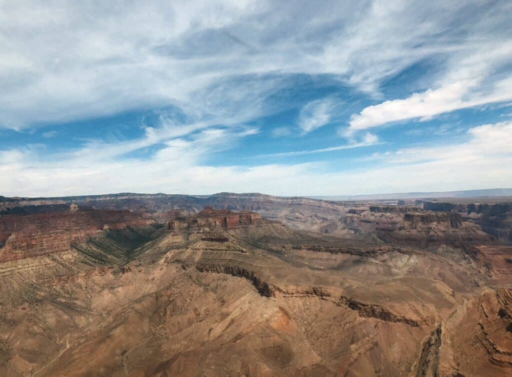 Arizona's Grand Canyon of red and brown rock formation under a blue sky with white clouds