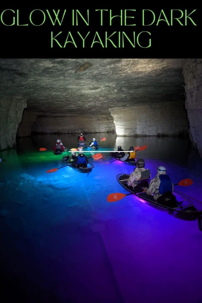 Glow in the dark kayaks reflecting a variety of colors in the water in a dark cave