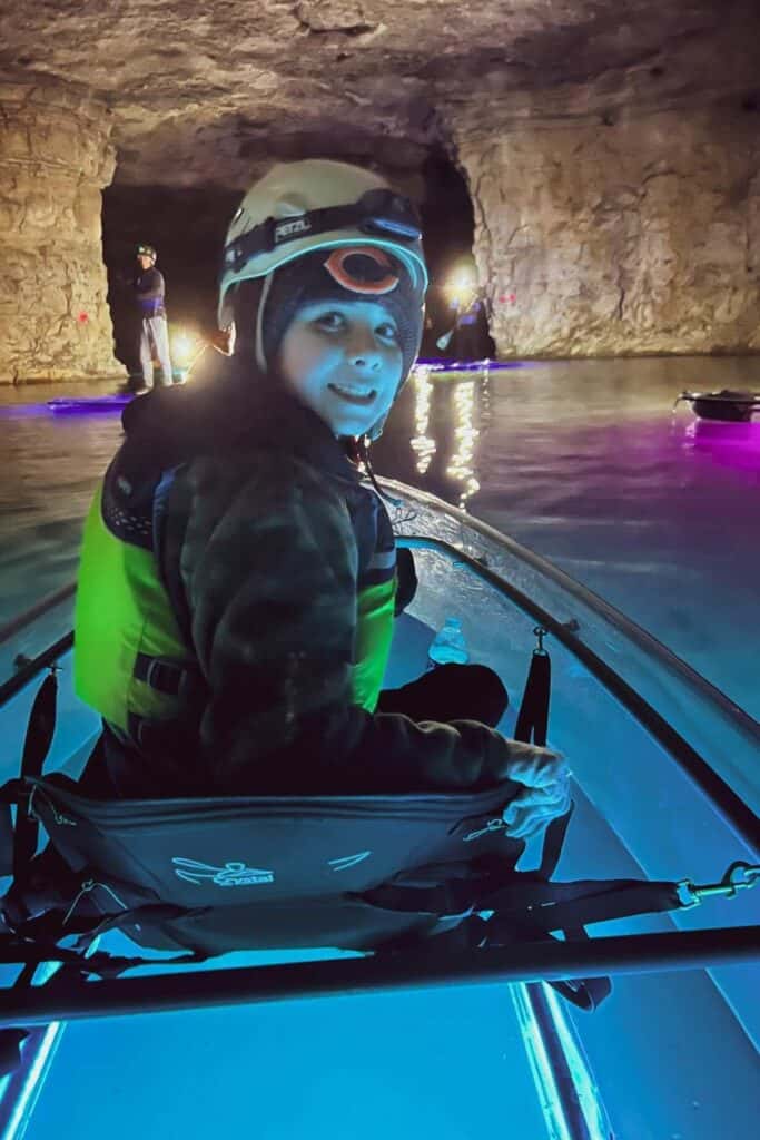 boy in a glow in the dark kayak wearing a white helmet