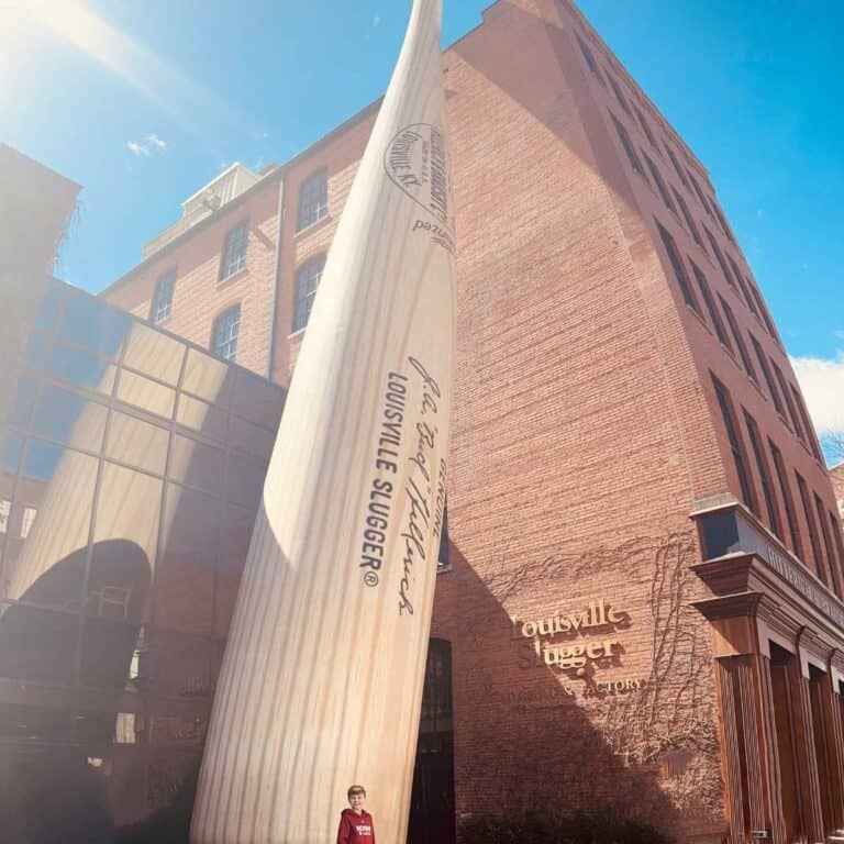giant light tan baseball bat next to a red brick building