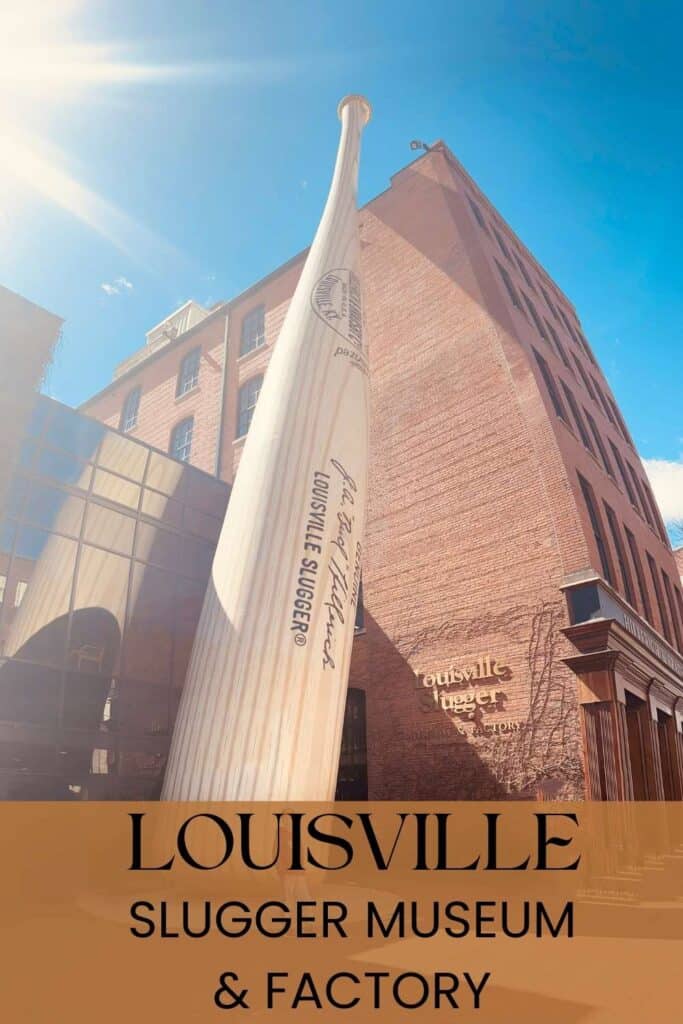 Giant baseball bat outside with a blue sky and a sign that says Louisville Slugger Museum and Factory