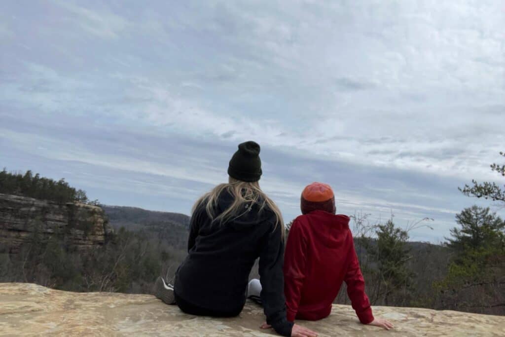 mom and son sitting enjoying the panoramic view from the top of Natural Bridge showing lush Kentucky forest