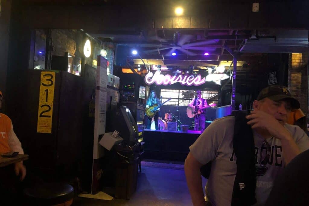 Interior of Tootsie's Orchid Lounge with historic photos and country musical memorabilia on the walls with a band of two guitar players playing on the stage