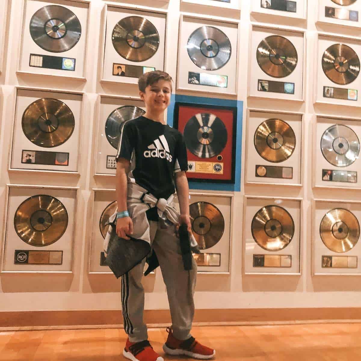 boy standing in front of wall of golden records at the Country Hall of Fame