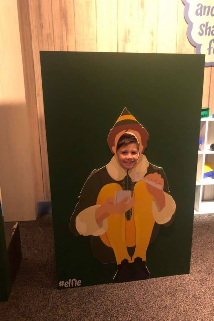 boy sticking his head through a festive elf cutout display at Gaylord Opryland Resort