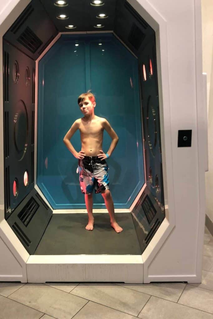 boy in a swimsuit standing inside a full-body dryer box at the pool in Gaylord Opryland Resort