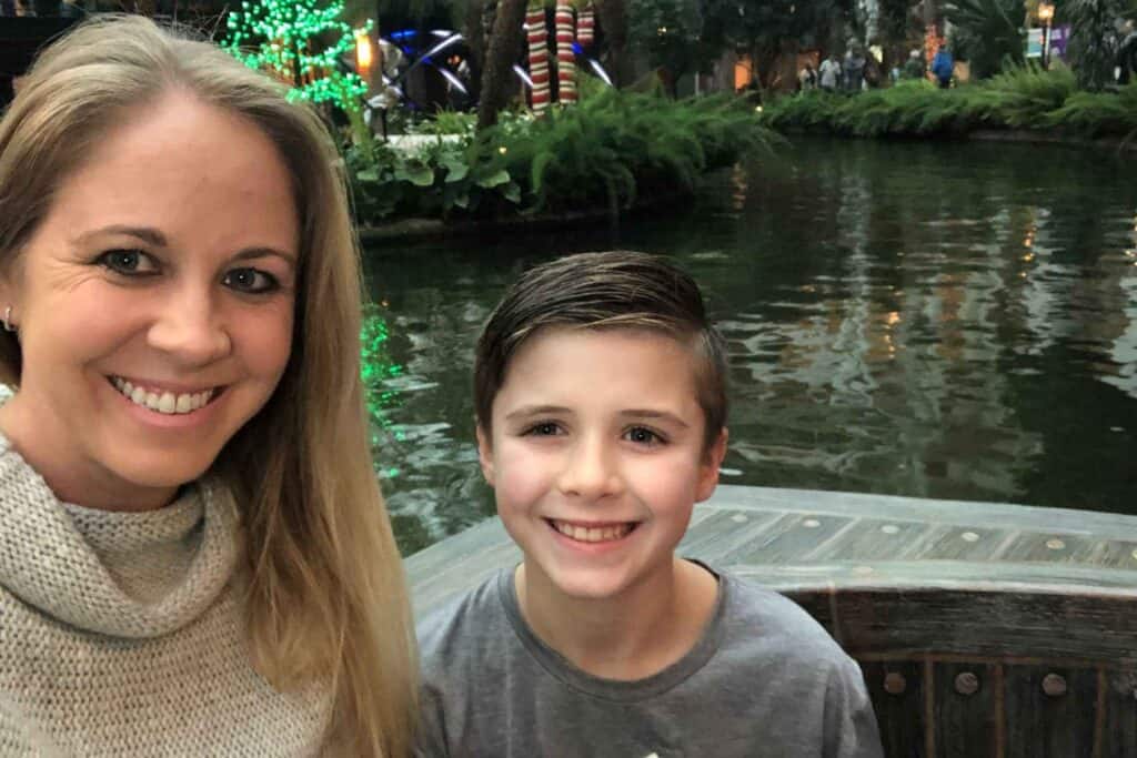 Mother and son, both wearing grey shirts, smiling with a river behind them at Gaylord Opryland Resort. 