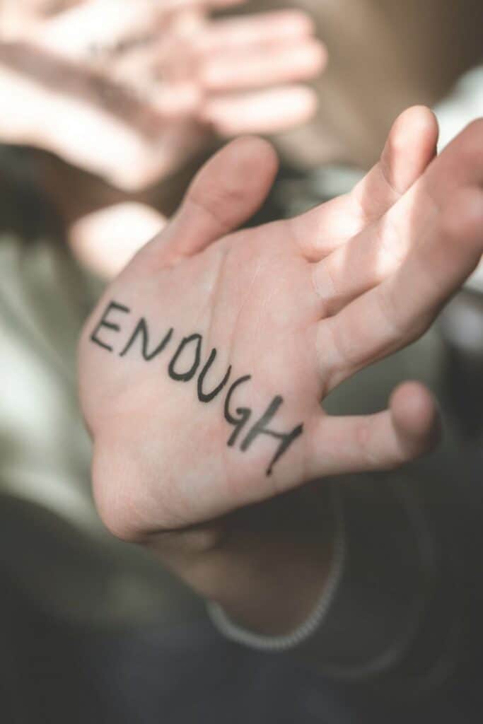 Woman's hand with the word "enough" written on the palm symbolizing choosing peace after a toxic relationship