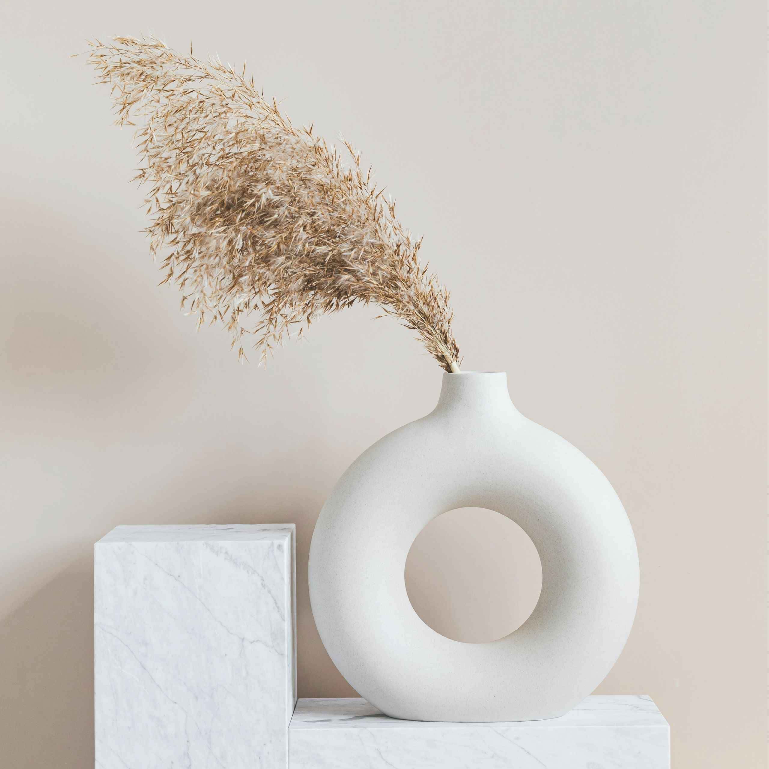 Minimalist white vase with dried pampas grass on marble surface representing a peaceful home and intentional living space. 