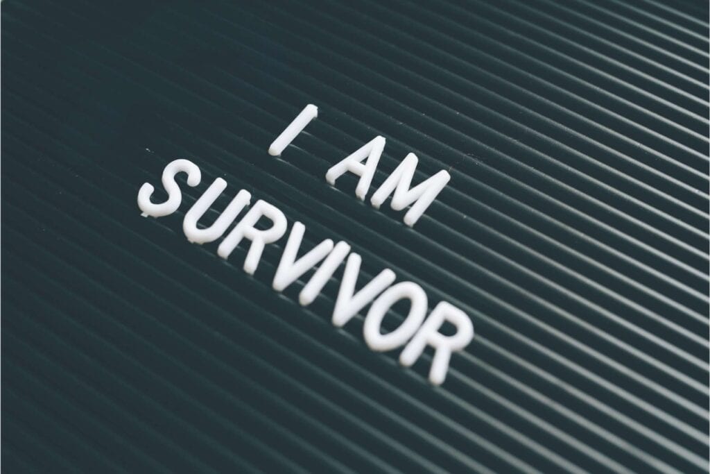 I am a survivor sign on a black textured board, symbolizing resilience, emotional strength, and healing after survival mode