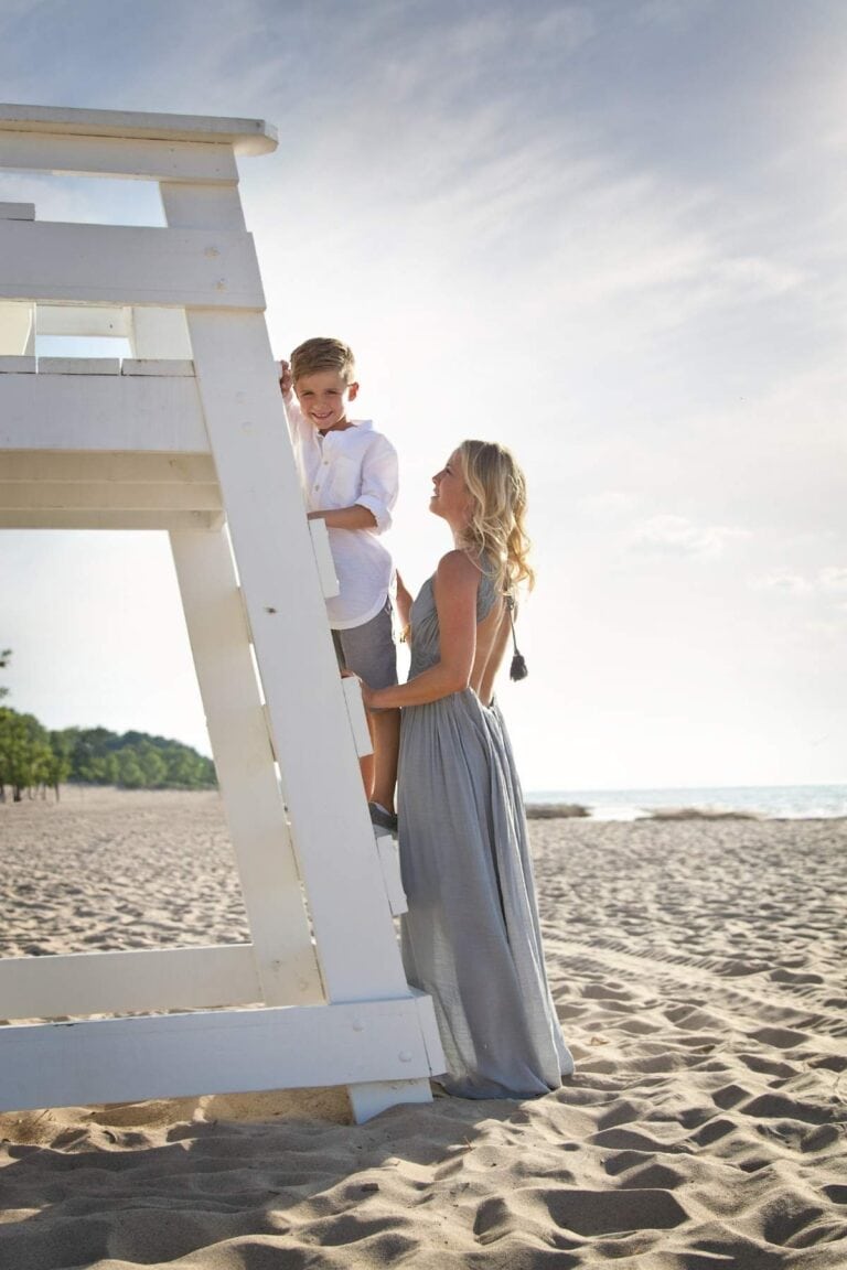mother supporting her son on beach lifeguard stand showing guidance, stability, and emotional connection
