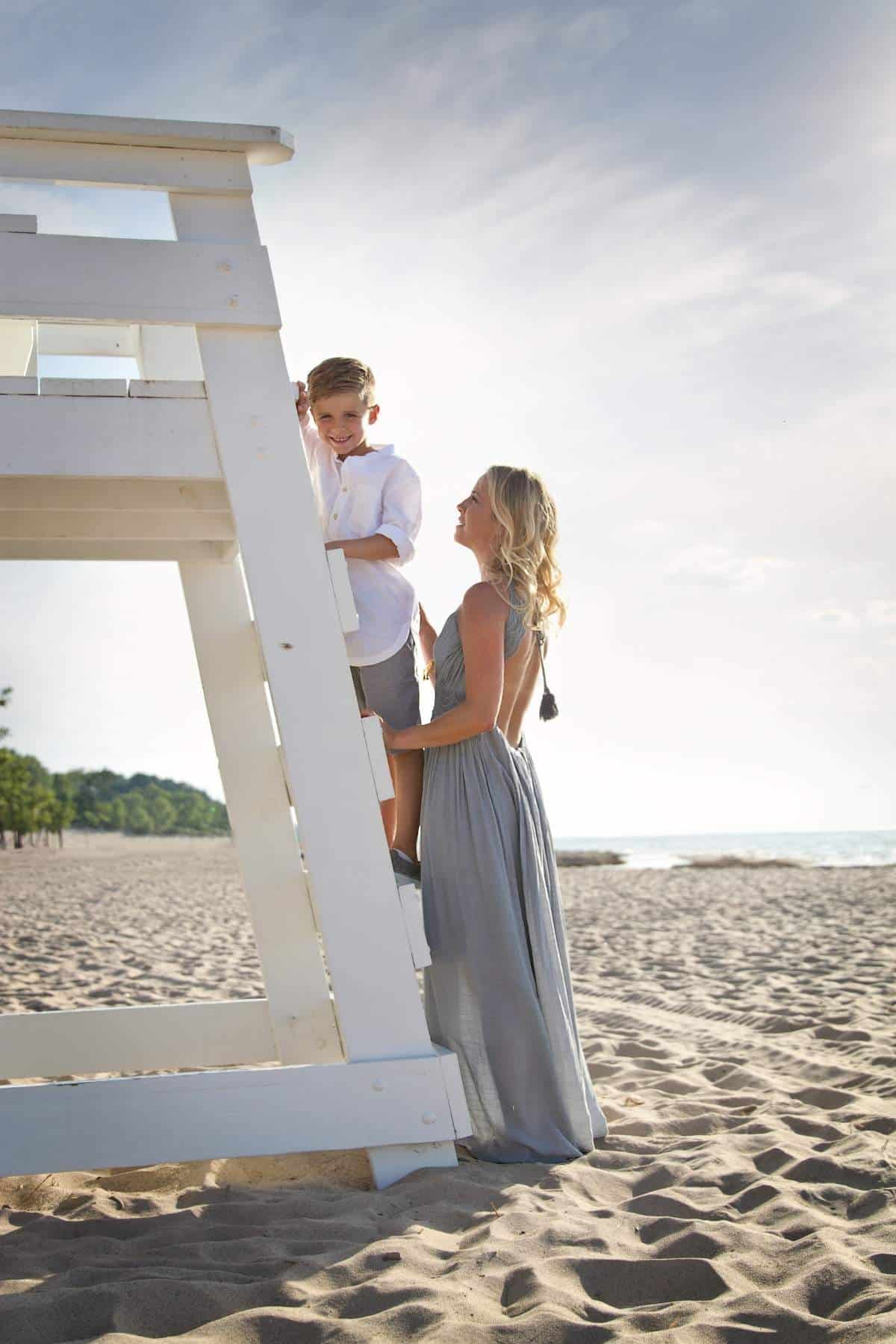 mother supporting her son on beach lifeguard stand showing guidance, stability, and emotional connection